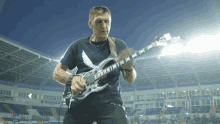 a man playing a guitar in a stadium with a shirt that says army on it