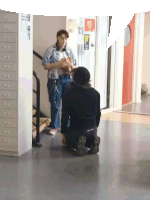 a woman standing next to a man kneeling down in front of a sign that says ' ambulance '