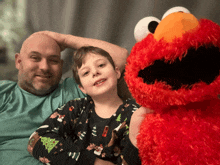 a man and a boy are sitting next to elmo