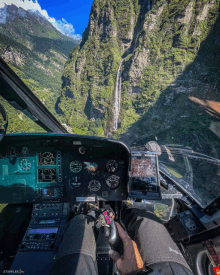 a person sitting in a cockpit of a helicopter looking out at a waterfall