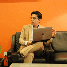 a man sitting on a couch with an apple laptop