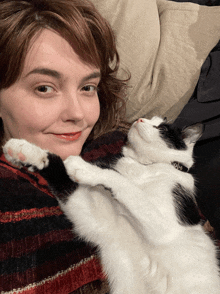 a woman is holding a black and white cat with a collar that says ' love ' on it