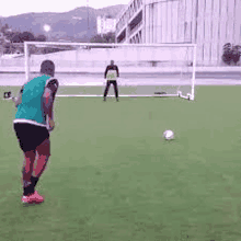 a soccer player is kicking a soccer ball in front of a goalie .