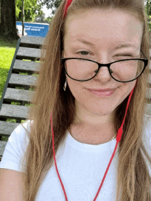 a woman wearing glasses winks at the camera with a sign in the background that says ' county hospital '