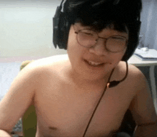 a shirtless man wearing headphones and glasses is smiling while sitting in a chair .