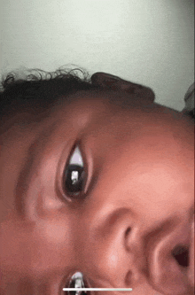 a close up of a baby 's face with a reflection of a person in his eyes .