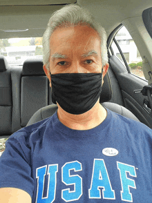 a man wearing a mask and a usaf shirt takes a selfie