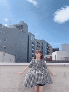 a girl in a plaid dress is standing on a wall