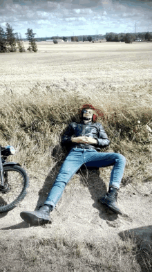 a man wearing a helmet is laying in the grass next to a bike