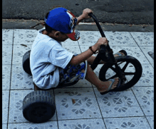 a young boy wearing a blue hat and sunglasses is riding a bicycle