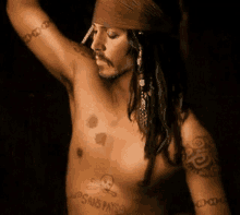 a shirtless man with a bandana on his head has a skull and crossbones tattoo on his chest