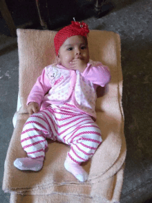 a baby wearing a pink outfit with a teddy bear embroidered on it