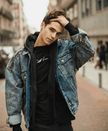 a young man wearing a denim jacket and a black shirt that says " just then " on it