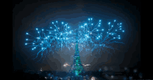 the eiffel tower is lit up with green lights and blue fireworks