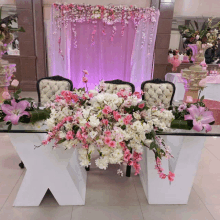 a table decorated with pink and white flowers with the letter x on it