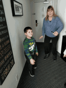 a woman and a boy are standing in a hallway with a sign on the wall that says the great day