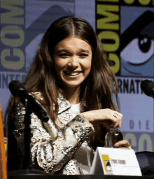 a woman sits at a table at comic con