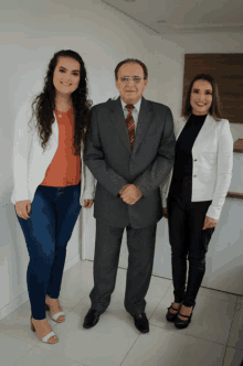 a man in a suit and tie is standing between two women