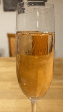 a glass of wine with bubbles in it is on a wooden table