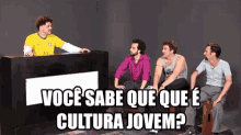 a group of men are sitting around a table with a sign that says você sabe que que e cultura jovem ?