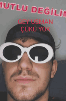 a man wearing sunglasses and a hat with the words mutlu degil on it