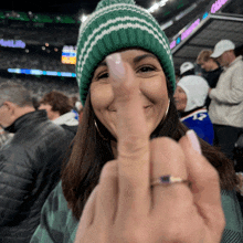 a woman wearing a green hat and a ring is making a heart with her finger