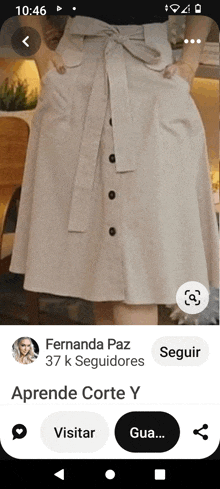 a screenshot of a woman wearing a beige skirt with buttons