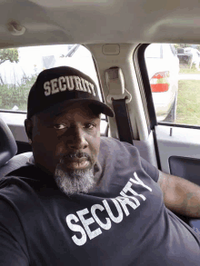 a man in a car wearing a security hat and a security shirt