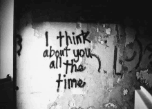 a black and white photo of a graffiti message on a wall that says `` i think about you all the time '' .