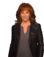 a woman with red hair is wearing a leather jacket