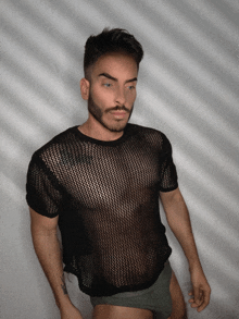 a man with a beard wearing a black mesh top