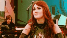 a woman with red hair is sitting in front of a microphone in a recording studio .