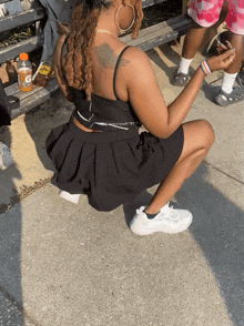 a woman squatting on the sidewalk with a gatorade bottle in the background