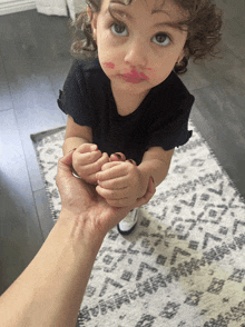 a little girl with lipstick on her face is being held by a person