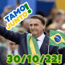 a man in a suit and tie holding a small brazilian flag .