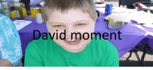 a boy in a green shirt is sitting at a table with the words david moment written on the bottom