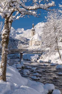 a snowy scene with a church in the background and a river in the foreground