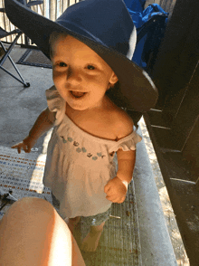 a baby wearing a blue hat and a white top