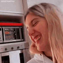 a woman laughs in front of a microwave that says come