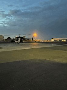 a black and white helicopter is on a runway at night