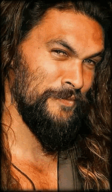 a close up of a man 's face with long hair and a beard .