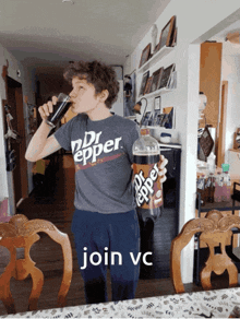 a boy wearing a dr pepper shirt drinks from a glass while holding a bottle of dr pepper