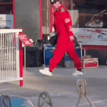 a man in a red jumpsuit is walking in front of a sign that says ' grayhound ' on it