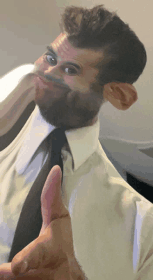 a man with a beard wearing a white shirt and black tie is giving a thumbs up