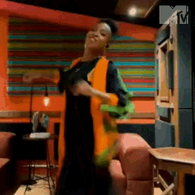 a woman is dancing in a room with a colorful wall behind her .