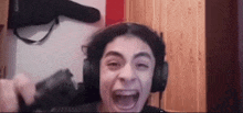 a young boy wearing headphones is screaming while holding a camera .