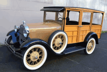 a woody station wagon with white tires is parked in front of a building