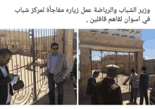 a man in a suit stands in front of a fence with arabic writing on it