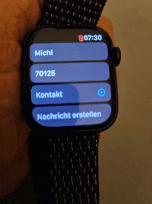 a person is holding a smart watch that says michi 70125 kontakt and nachricht erstellen