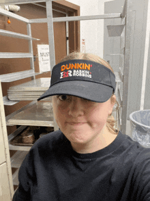 a girl wearing a dunkin ' donuts visor makes a funny face